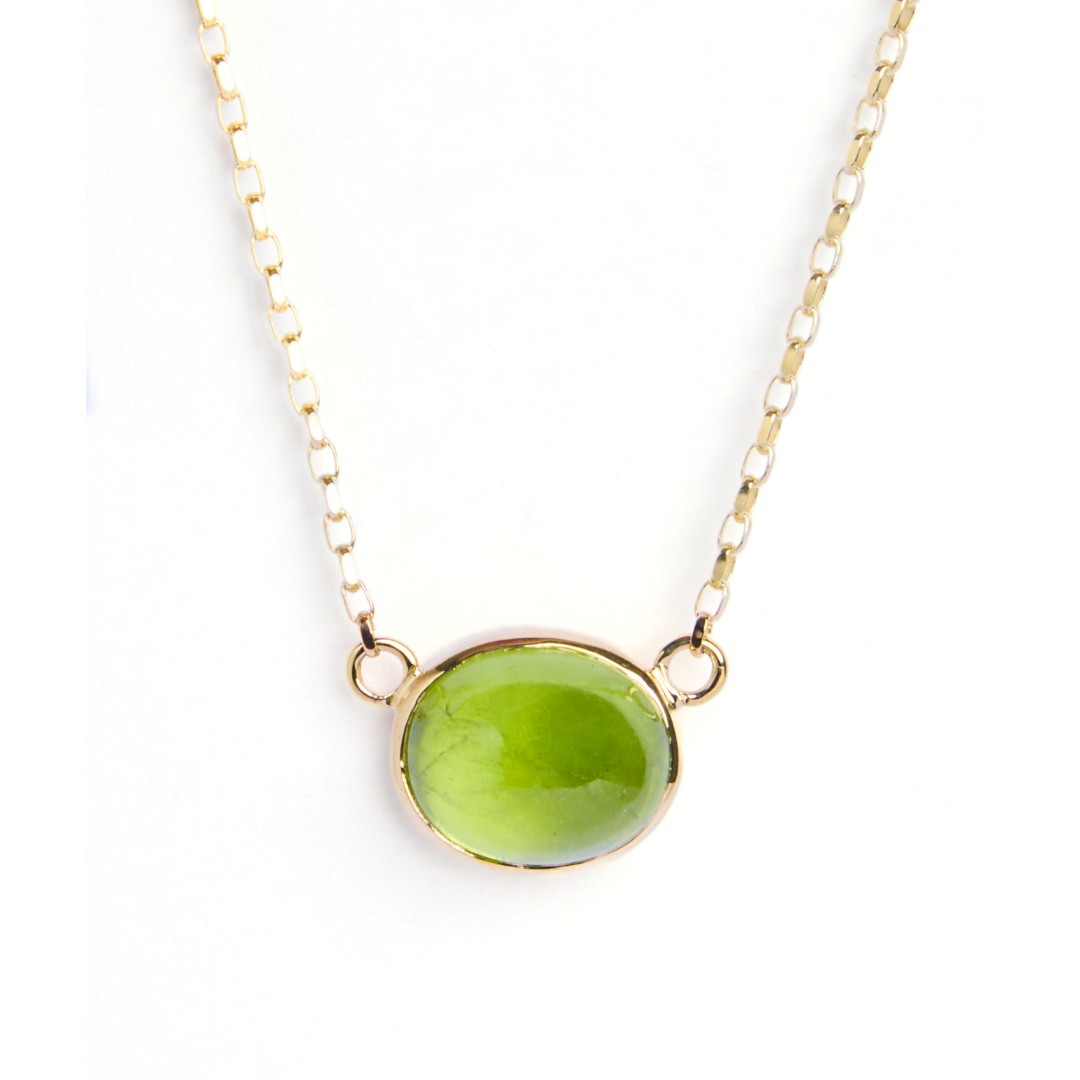 The Whispering Moss 9ct Yellow Gold Necklace by Madeleine Fine Jewellery features an oval cabochon peridot in a sleek gold bezel, centered on a chain with two petite gold loops.