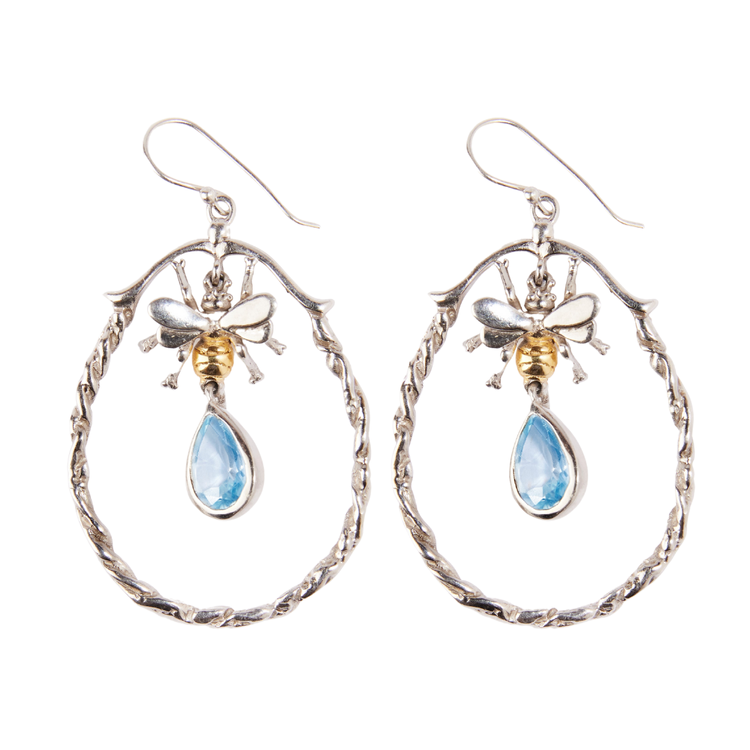 The Wildlife Large Bee Hoop Drops by Watermelon Tropical feature detailed bees with gold accents on silver hoops, each set with a blue teardrop gemstone for a unique, elegant touch.
