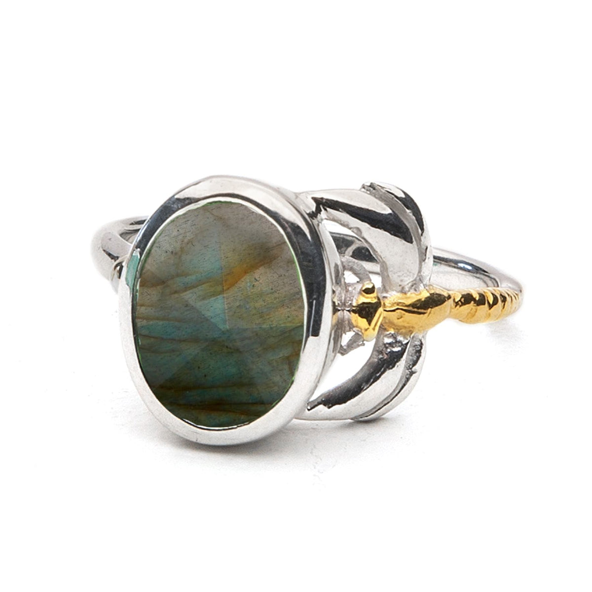 A close-up image of the Daydream Ring in various gemstones by Gallardo & Blaine Designs featuring an oval-shaped labradorite gemstone set in a silver band with gold accents designed to resemble leaves or petals. This timeless piece displays a range of blu