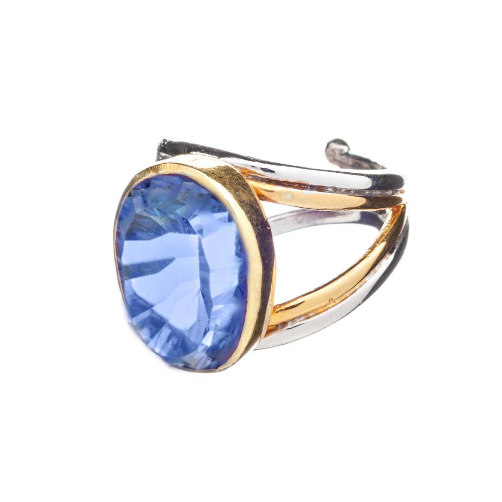 A close-up image of a chunky statement ring featuring a large, oval-shaped blue gemstone set in a band that combines sterling silver and gold elements. The band has a unique, open design, adding an elegant touch to the overall appearance of the Dewberry R
