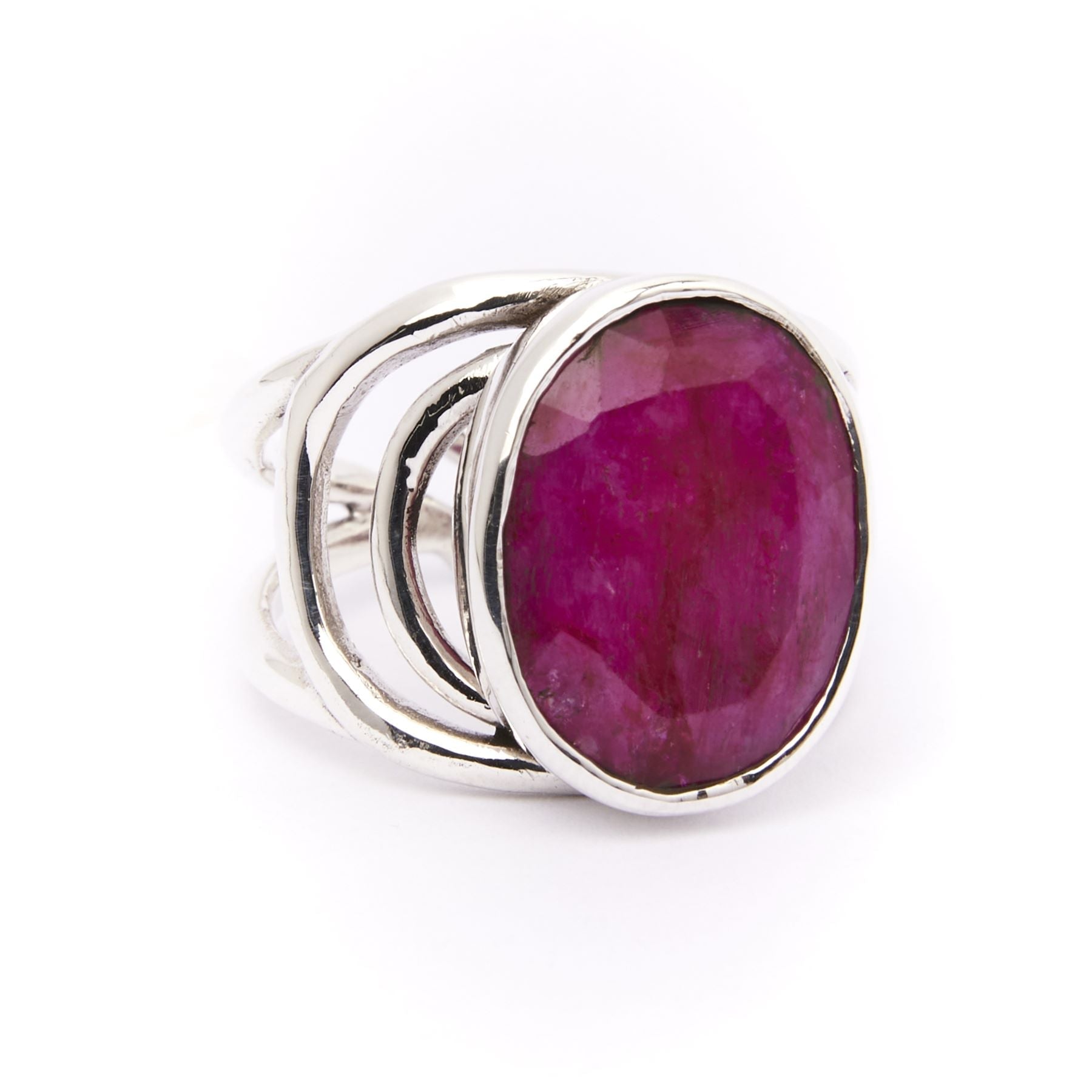 A sterling silver ring featuring a large, oval-shaped, faceted red gemstone at the center. The band is adjustable and consists of multiple intertwined silver strips, giving it a unique and modern design. This chunky statement ring is sure to turn heads. T