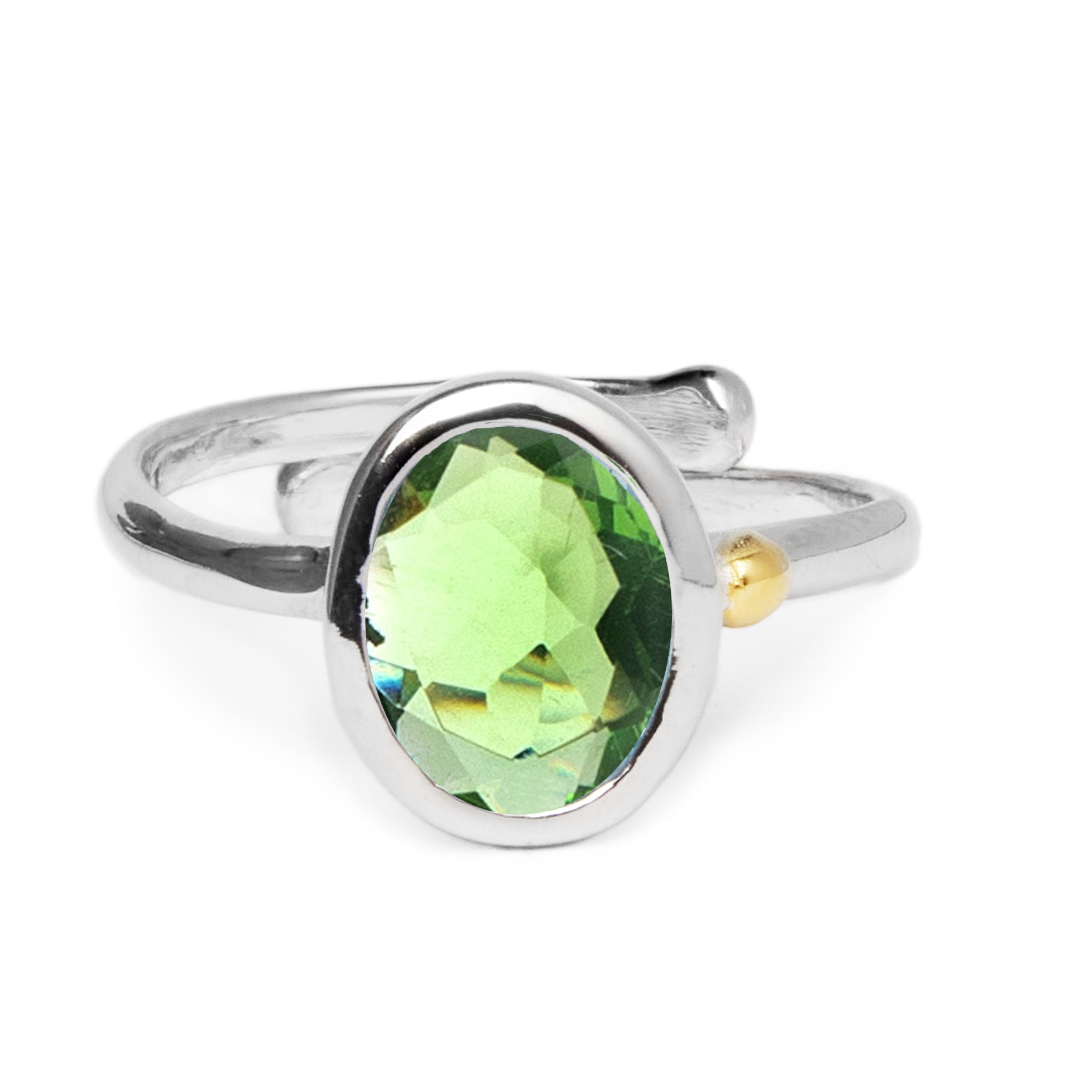 The Dream Ring in various gemstones by Gallardo & Blaine Designs is set with a large, oval-shaped green gemstone at its center. The band of the ring is simple and smooth, boasting a minimalist design with a small gold accent on one side near the gemstone 