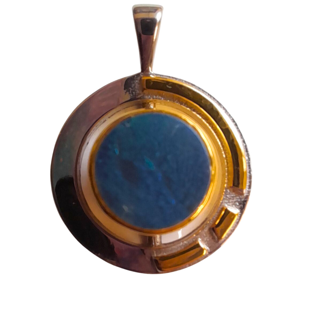 The Elodie Pendant in silver gold & various gemstones by Gallardo & Blaine Designs features a round, blue gemstone set in a circular, silver-colored metal frame. The Art Deco design includes a gold-colored band encircling the gemstone and extending into t