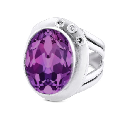 The Eyetelia Ring in various gemstones by Gallardo & Blaine Designs features a large, faceted oval purple gemstone set in the center. This silver statement cocktail ring boasts a modern design with a split shank and three small round diamonds embedded in 