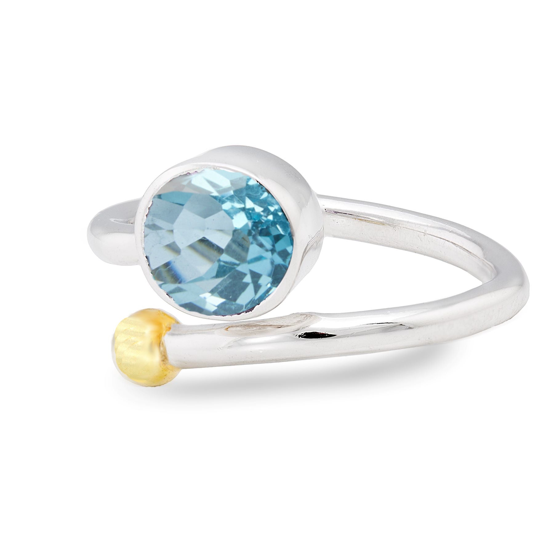 The Gallardo & Blaine Designs Honeysuckle Ring in Silver Gold & gemstones features an open band design with a blue, faceted gemstone set in a round bezel on one end and a small, gold-tone sphere on the other. This elegant adjustable gemstone ring captures