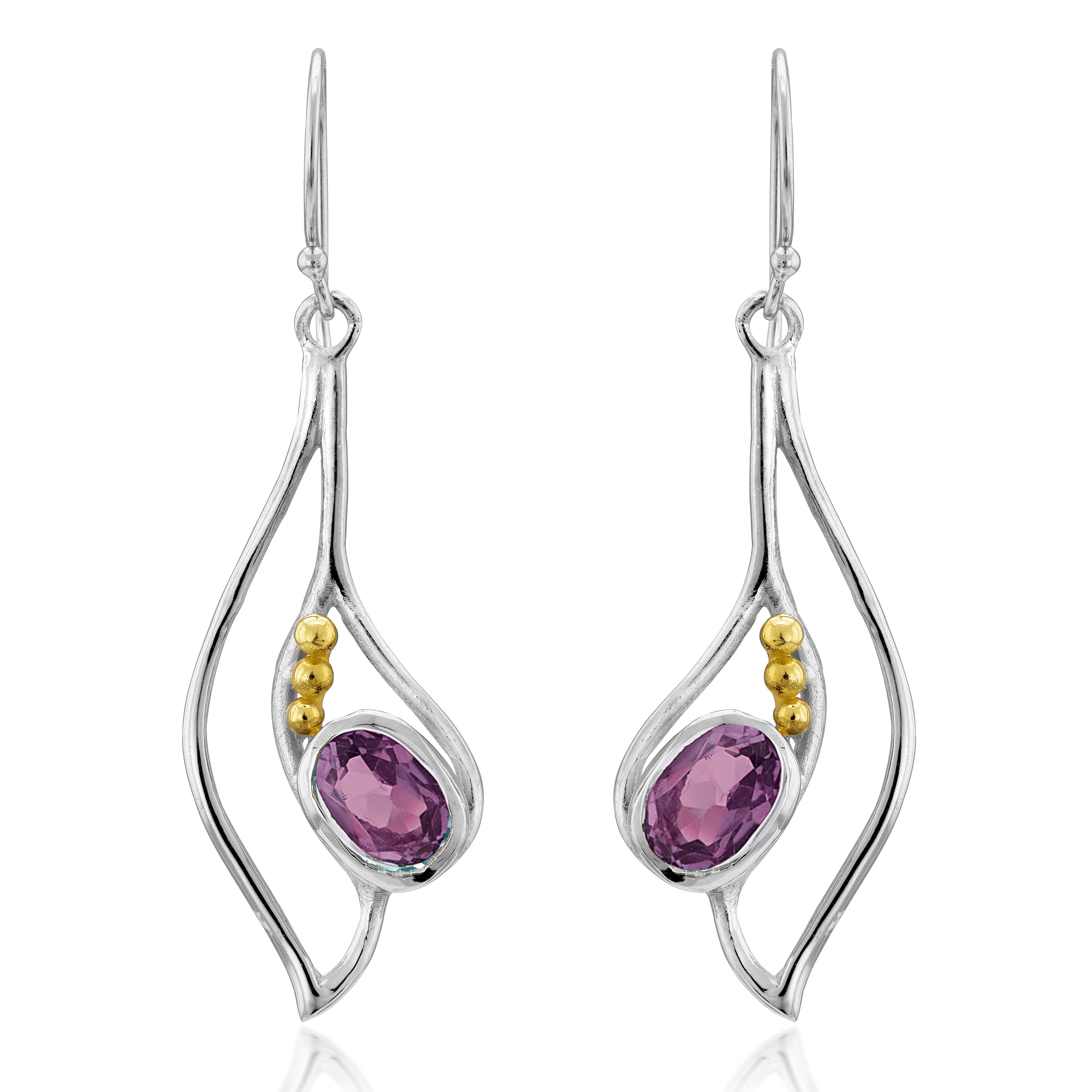 The Iris Earrings in various gemstones by Gallardo & Blaine Designs are a pair of silver & gold drop earrings featuring an organic, wavy design. Each earring has an oval-shaped purple gemstone set in the center and accented with three small gold beads on 