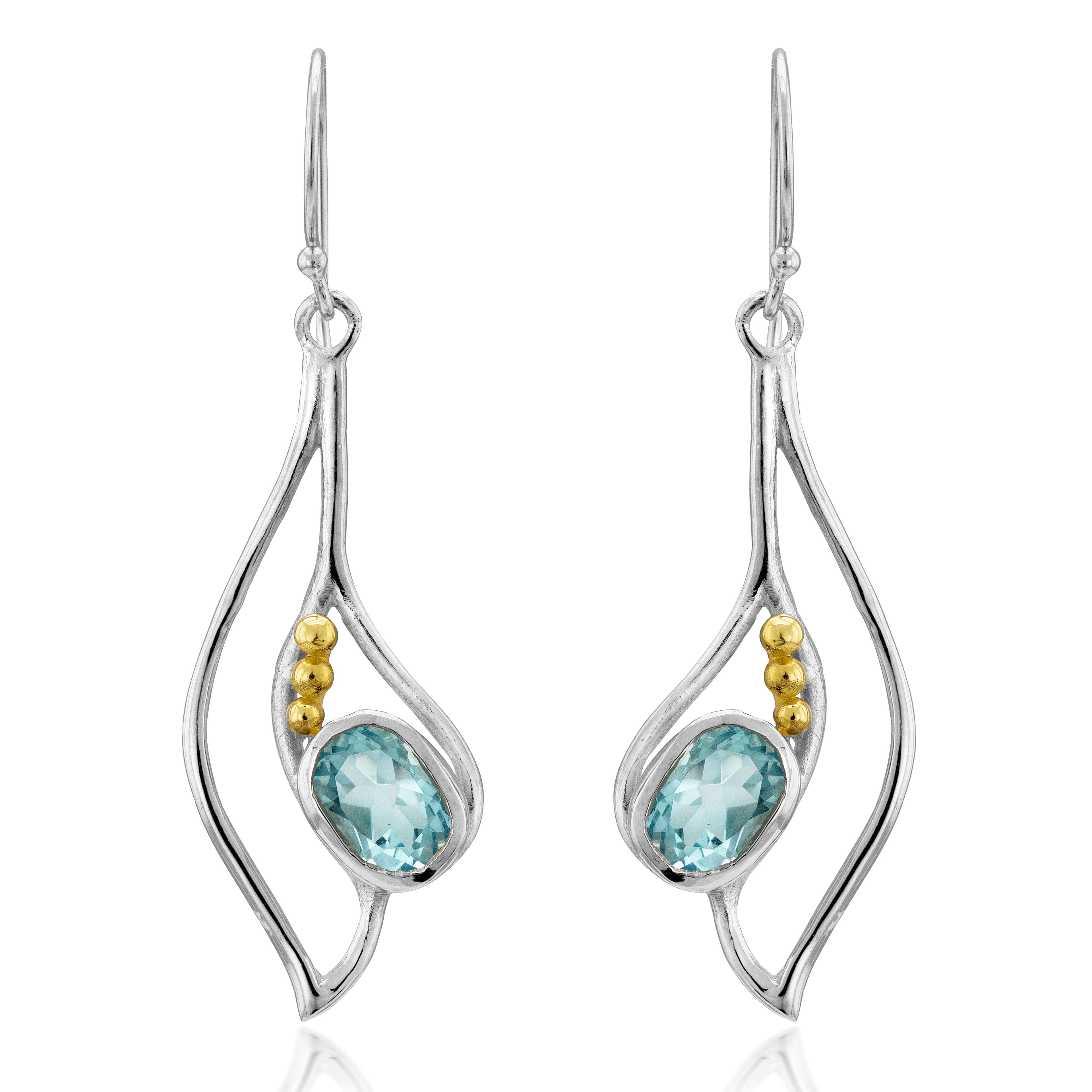 The Iris Earrings in various gemstones are elegant silver drop earrings featuring oval blue gemstones set in the center, each adorned with three small gold beads on the sides. These gemstone earrings hang from delicate hooks, showcasing a modern, fluid de