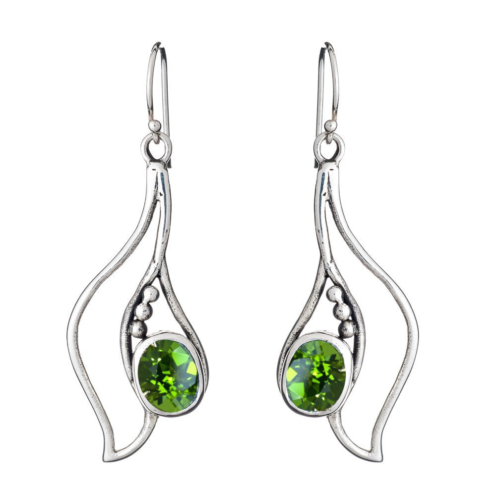 The Iris Earrings in various gemstones by Gallardo & Blaine Designs are a pair of silver dangling gemstone earrings with an artistic, flowing design. Each earring features three small silver beads and a single, oval-shaped green gemstone set in the center
