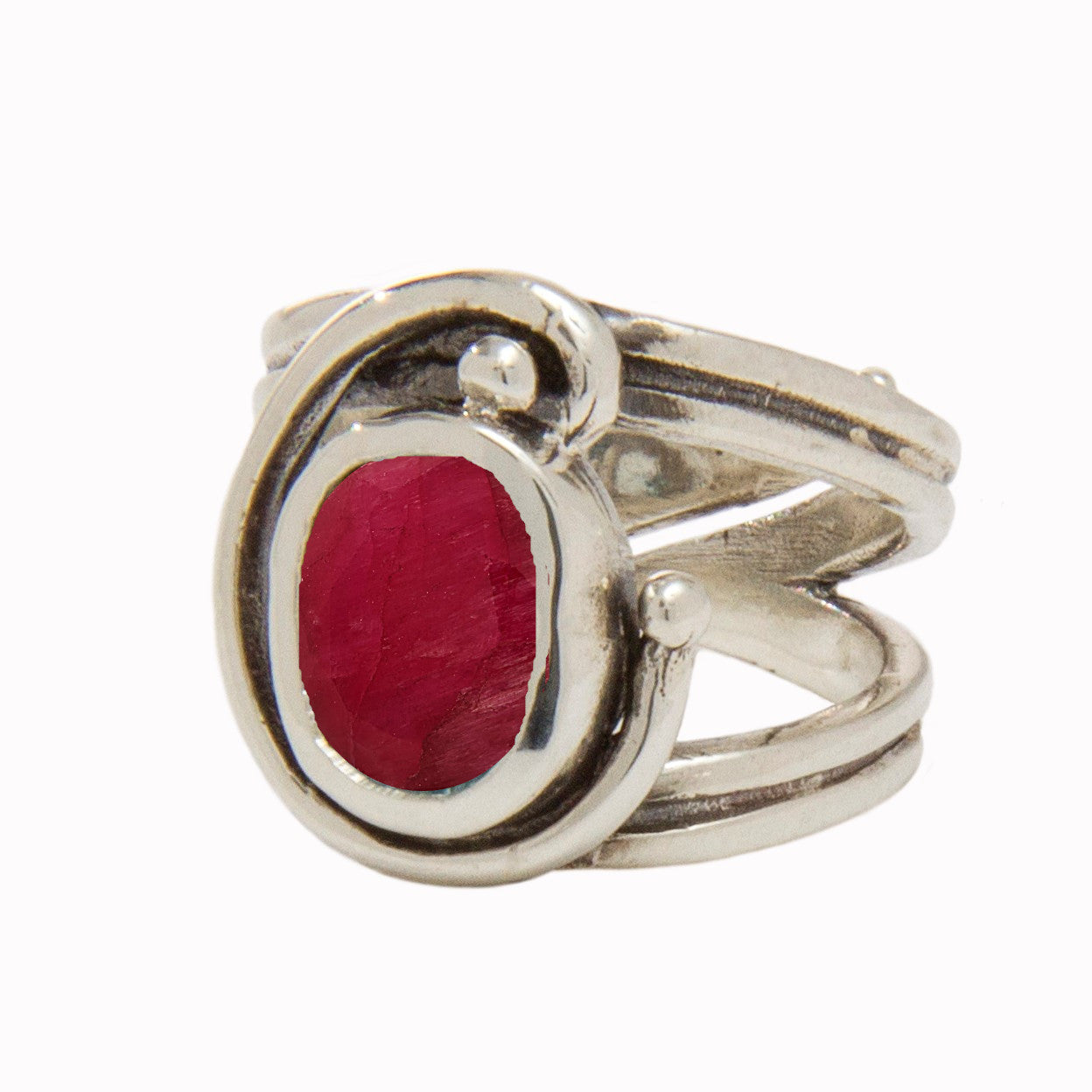 A silver Jasmine Ring in various gemstones by Gallardo & Blaine Designs featuring a large, oval-shaped red gemstone at its center. The band has a unique, intertwined design, giving it an elegant and intricate appearance. The ring appears to be polished, e
