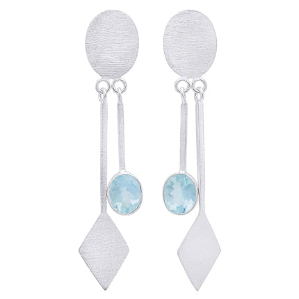 A pair of modern fashion jewelry, the Karo Earrings in various gemstones by Gallardo & Blaine Designs feature brushed sterling silver ovals at the top. Each earring has a long, narrow bar dangling from the oval, ending in a diamond shape and a light blue 