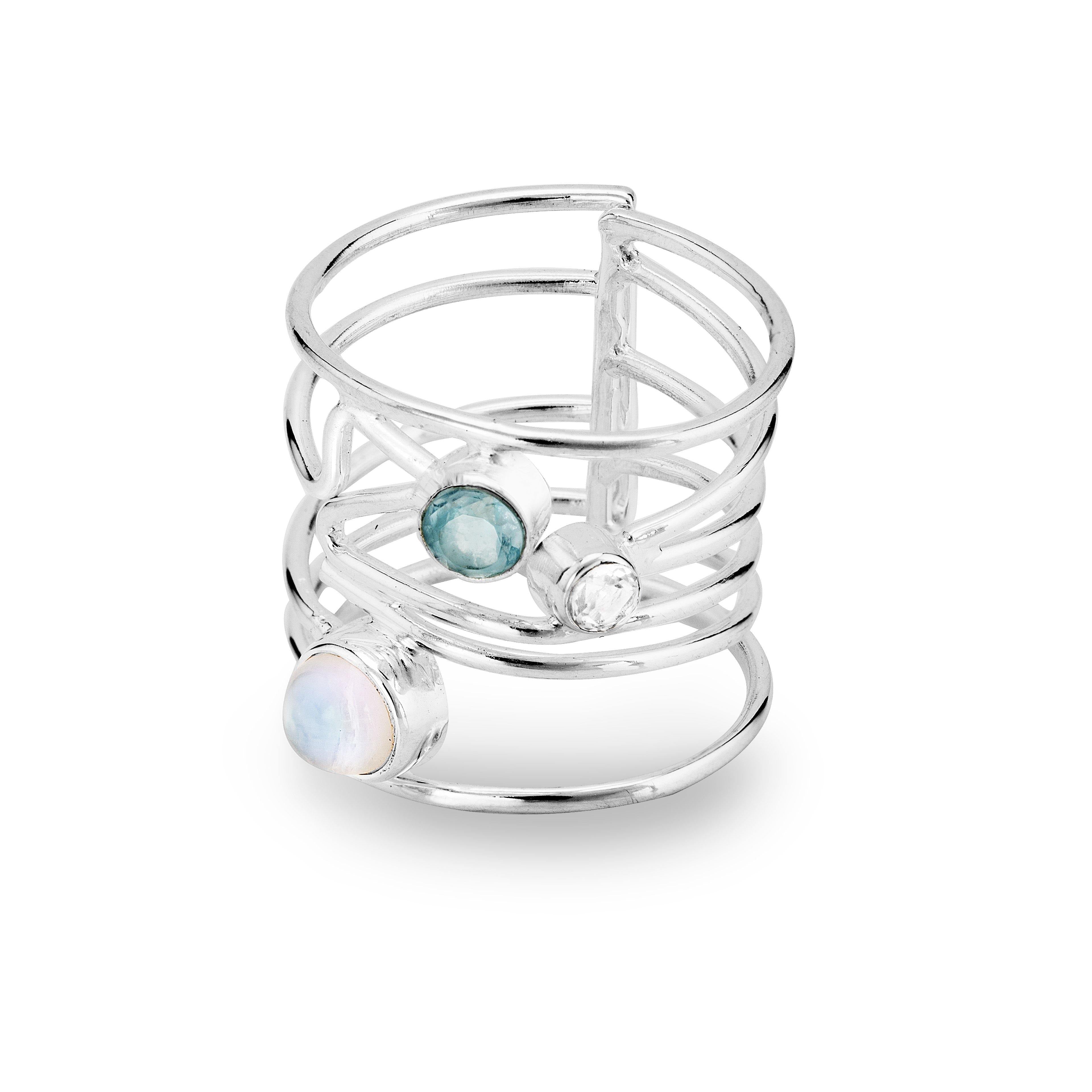 A Lattice Ring in various gemstones by Gallardo & Blaine Designs featuring three gemstones: a white opal, a blue topaz, and a clear quartz. The band has an open, lattice design with the stones set at different points across the layers, creating a contempo