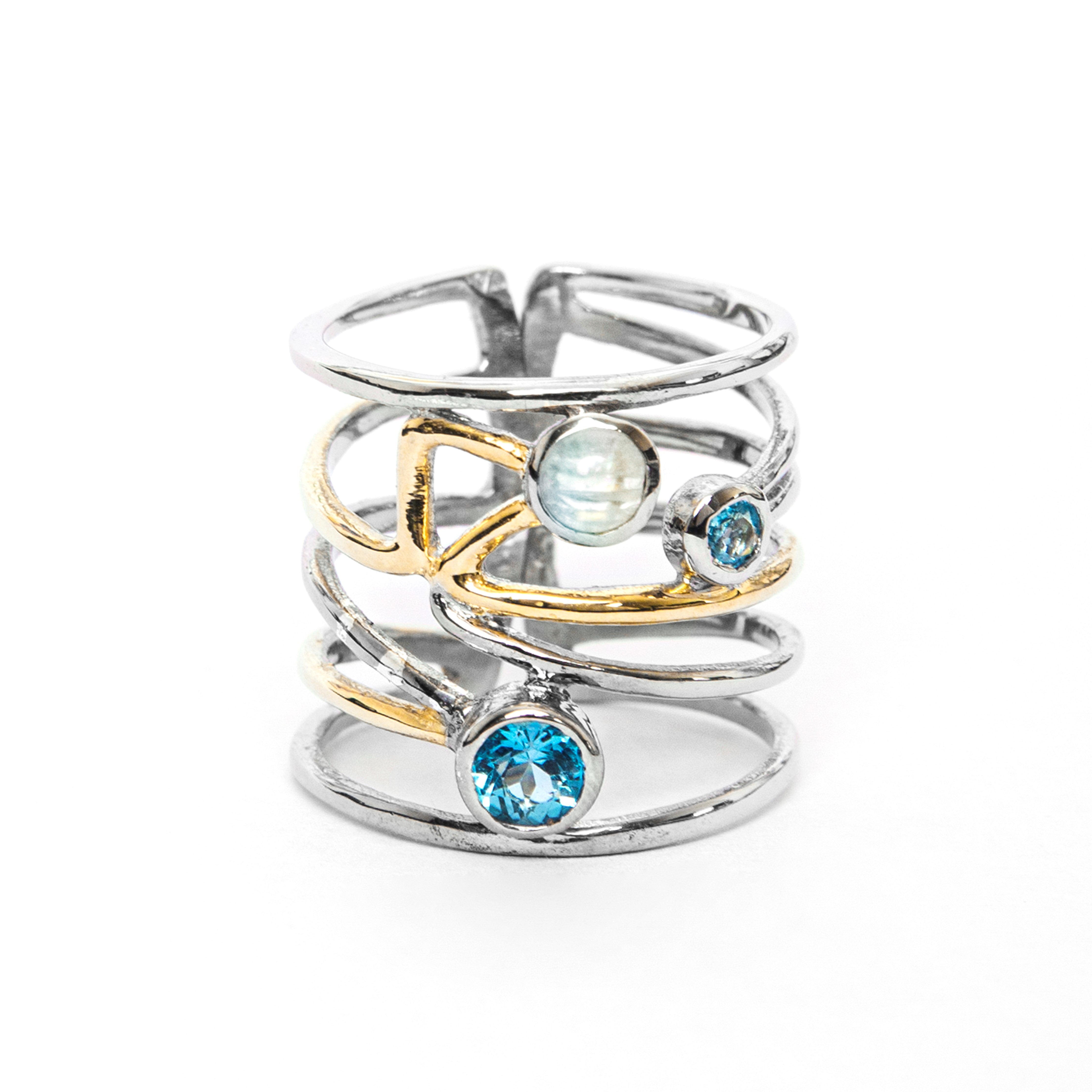 A Lattice Ring in various gemstones featuring an intricate multi-band design with gold accents, this piece showcases a contemporary design. Adorned with three gemstones: a blue gemstone at the base, a smaller blue gemstone on one side, and a round opalesc