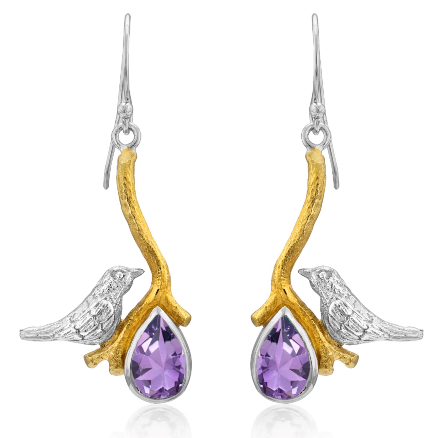 A pair of elegant Lovebird Earrings in various gemstones from Gallardo & Blaine Designs featuring a design with silver birds perched on gold branches. Each branch holds a teardrop-shaped purple gemstone, adding a touch of color and sophistication to these