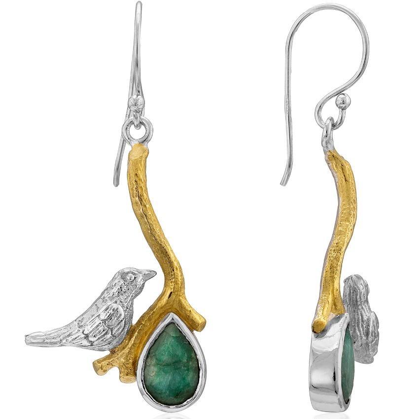 The Lovebird Earrings in various gemstones by Gallardo & Blaine Designs features a bird sitting on a golden branch. Each earring boasts a teardrop-shaped green gemstone hanging from the branch. The bird and branch design is silver with gold accents, creat