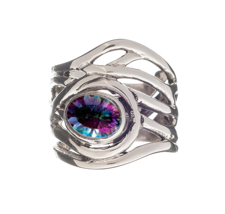 A chunky statement ring with a silver, overlapping band design holds a central gemstone that has a vibrant, multicolored pattern resembling an eye. This medieval-inspired jewelry piece is both bold and intricate. The Mayhem Ring in various gemstones by Ga