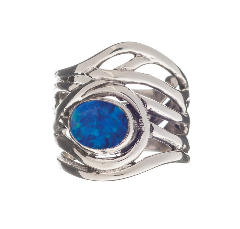 The Mayhem Ring in various gemstones by Gallardo & Blaine Designs features an intricate, wavy band design, set with a central oval blue opal gemstone. This chunky statement ring displays vibrant blue and green hues, adding a bold touch to any medieval-ins