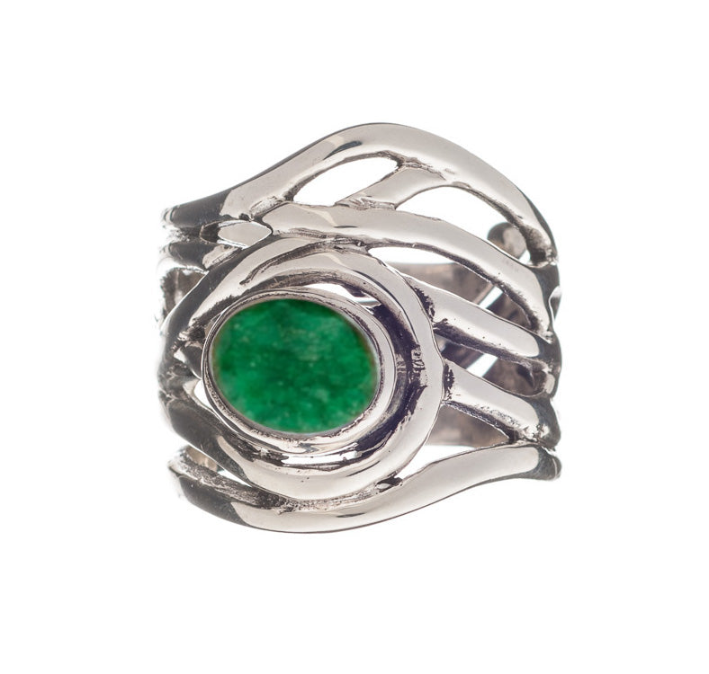 A chunky statement ring with an intricate, wavy band design, featuring an oval-shaped green stone set in the center. The Mayhem Ring in various gemstones by Gallardo & Blaine Designs has an adjustable silver band whose bright green gemstone contrasts bril