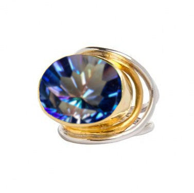 A sterling silver and gold Gallardo & Blaine Designs Party Ring in various gemstones with a large, faceted, oval-shaped gemstone displaying a sparkling array of blue, purple, and pink hues. The band features an intricate swirl design holding the gemstone 