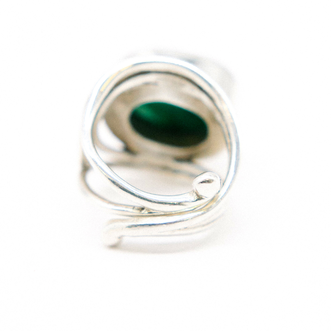 Close-up of the Party Ring by Gallardo & Blaine Designs, featuring a chunky statement with an intricate swirl design and a green oval gemstone at its center. The adjustable band enhances its versatile elegance against a plain white background.