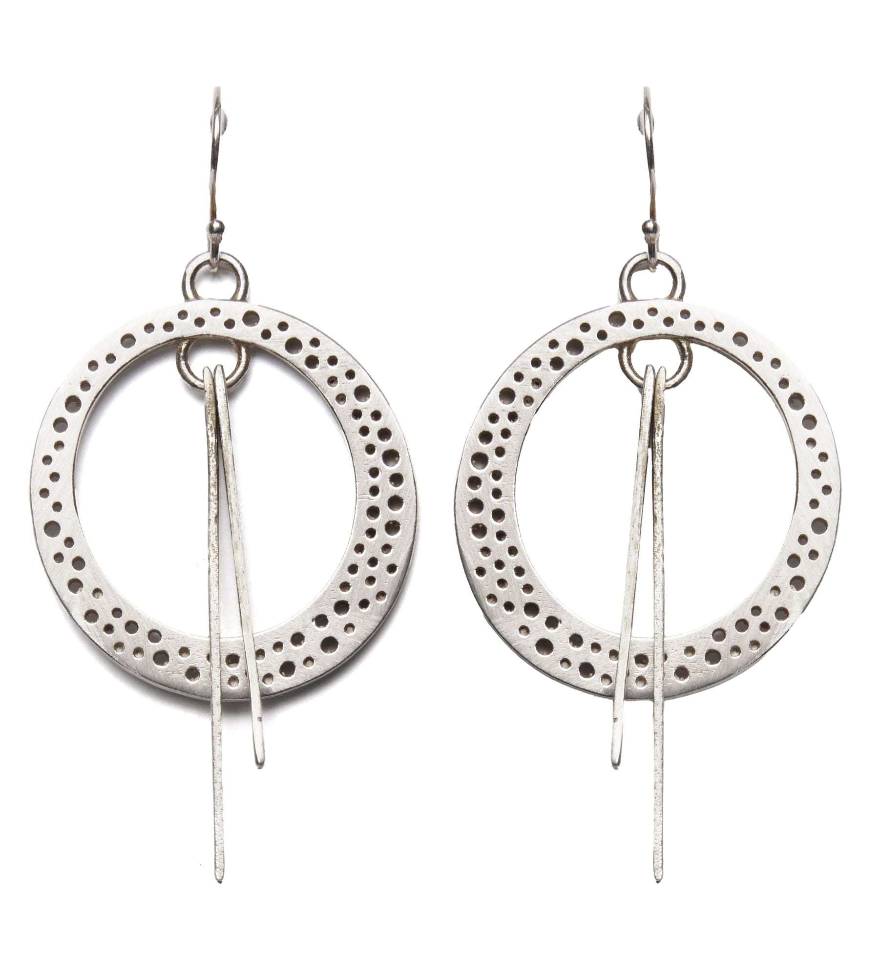 A pair of Rivera Earrings by Gallardo & Blaine Designs featuring large, circular hoops with Art Deco-inspired perforated patterns along the edges. Each hoop has two thin, elongated silver pieces hanging from the center. The earrings are suspended from sim