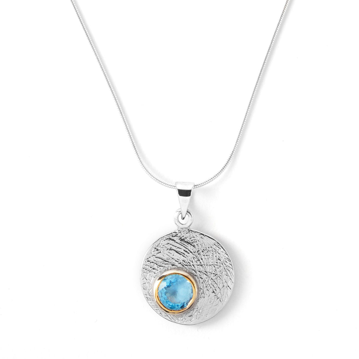 The Selene Necklace Silver - Small in various gemstones by Gallardo & Blaine Designs features a silver pendant with a textured surface and a small, embedded blue stone encircled by a gold bezel. Hanging gracefully from a Sterling silver chain, it combines