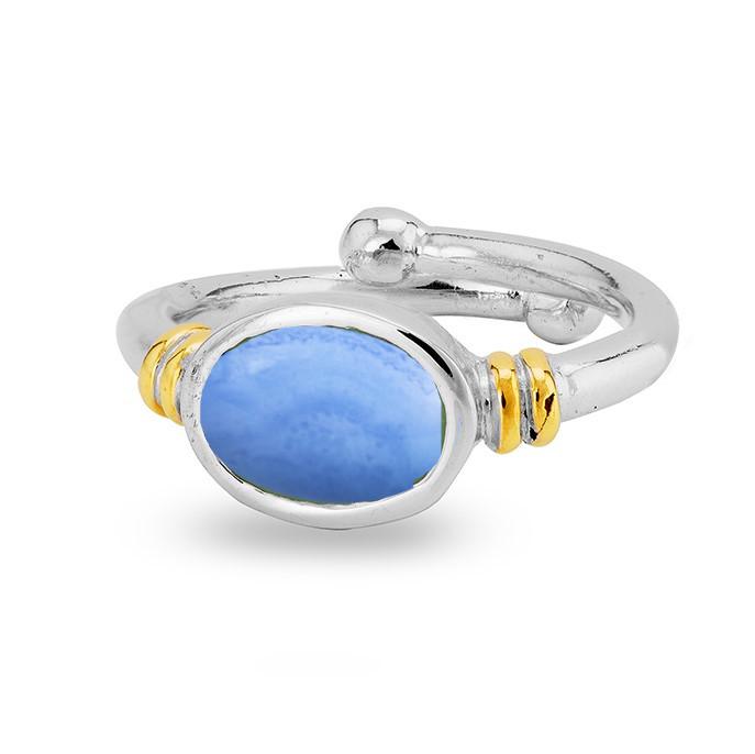 A silver, adjustable ring featuring a polished oval-shaped blue gemstone at its center. This Senna Ring in various gemstones by Gallardo & Blaine Designs includes gold-tone accents on either side of the gemstone, adding a touch of elegance to the overall 