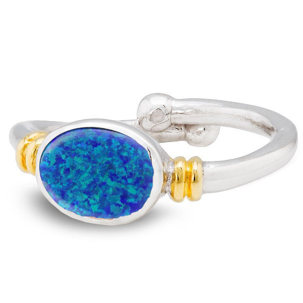 A silver, Art Nouveau Senna Ring in various gemstones by Gallardo & Blaine Designs featuring a blue oval opal stone set in the center. The band has gold accents on each side of the gemstone, and the split shank design offers adjustable comfort. The ring b
