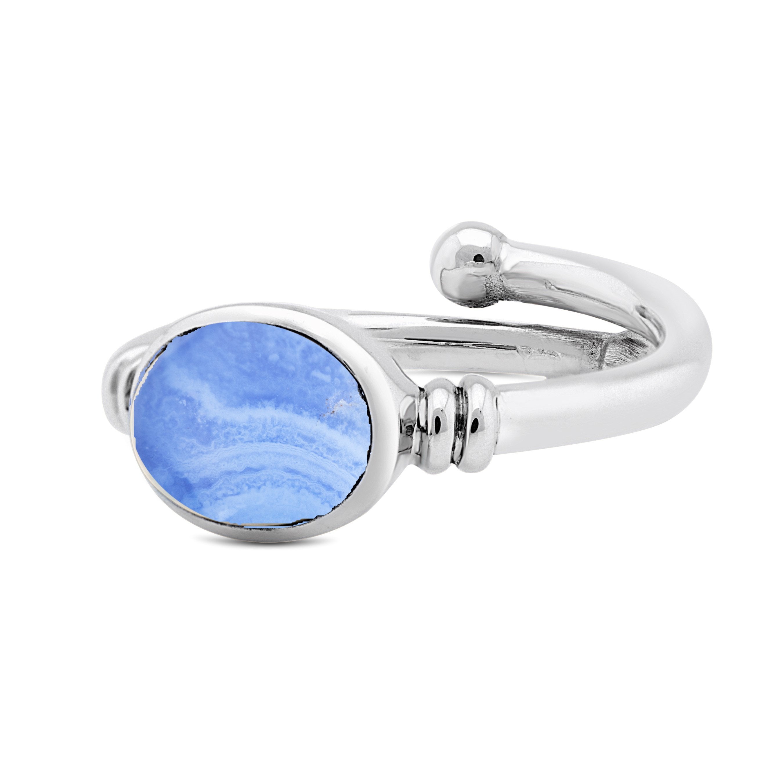 The Senna Ring in various gemstones by Gallardo & Blaine Designs features a polished silver gemstone ring with a large, oval-shaped blue stone adorned with white swirls. The band of the ring is smooth and splits near the setting, creating an open-ended de