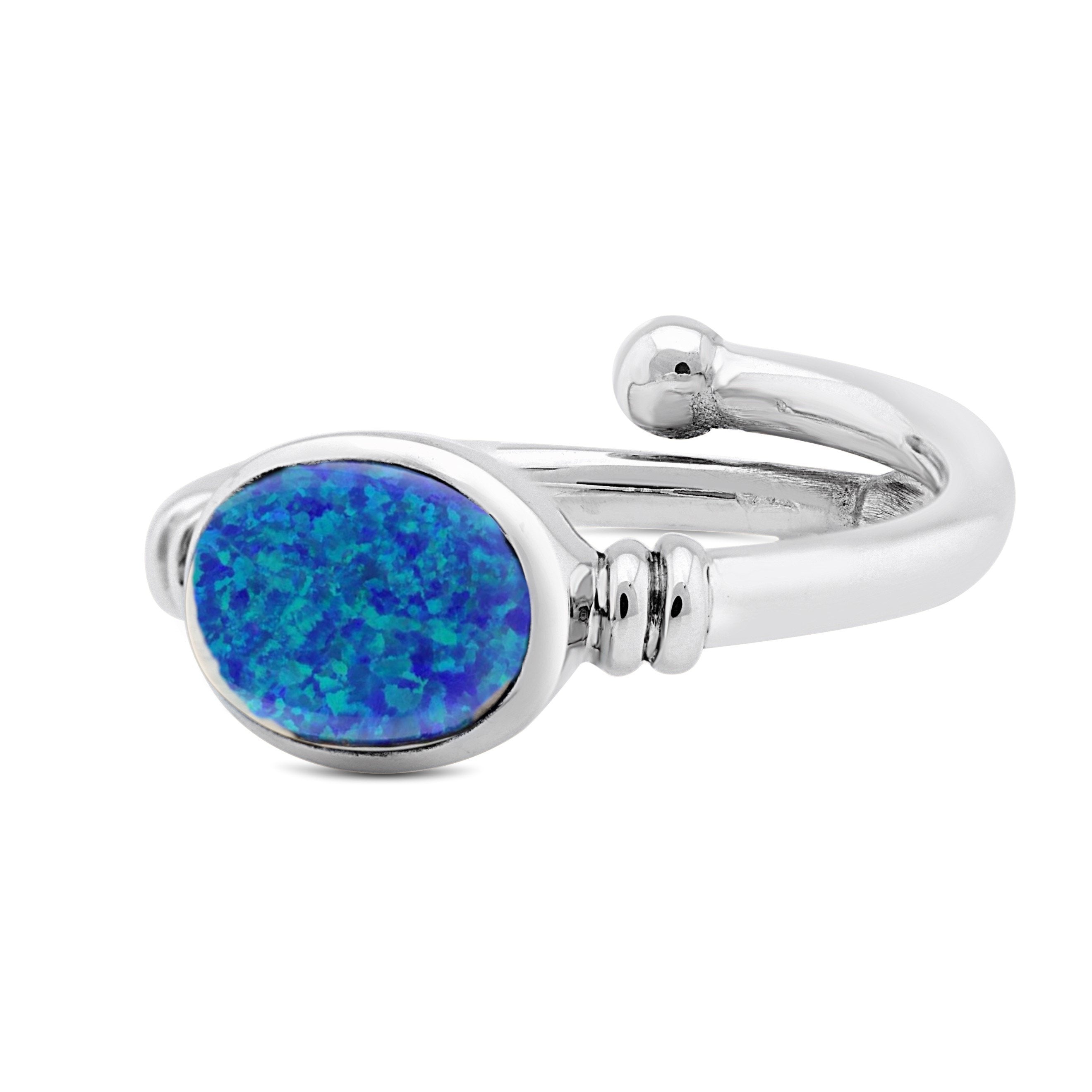 A Senna Ring in various gemstones with a large, oval-shaped blue opal stone set in the center from Gallardo & Blaine Designs. The opal exhibits a range of colors from deep blue to green, surrounded by a smooth, polished silver band with minimalist detaili