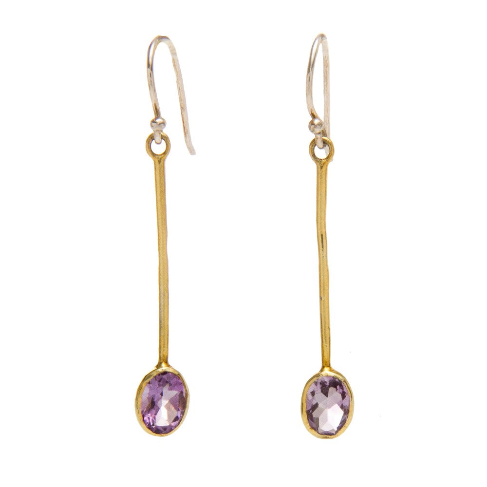 Introducing the Sequola Earrings in various gemstones by Gallardo & Blaine Designs: a pair of elegant, thin, gold drop earrings with oval-shaped, purple gemstones at the end. Each earring features a delicate hook for wearing. The sterling silver accents a