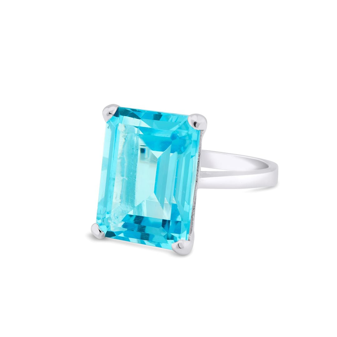 The Gallardo & Blaine Designs Stellar Ring in Hydro Blue Topaz features a large, rectangular-cut blue topaz held by four prongs. The gemstone is faceted, beautifully reflecting light, and giving the ring a luxurious and elegant appearance. Crafted from st