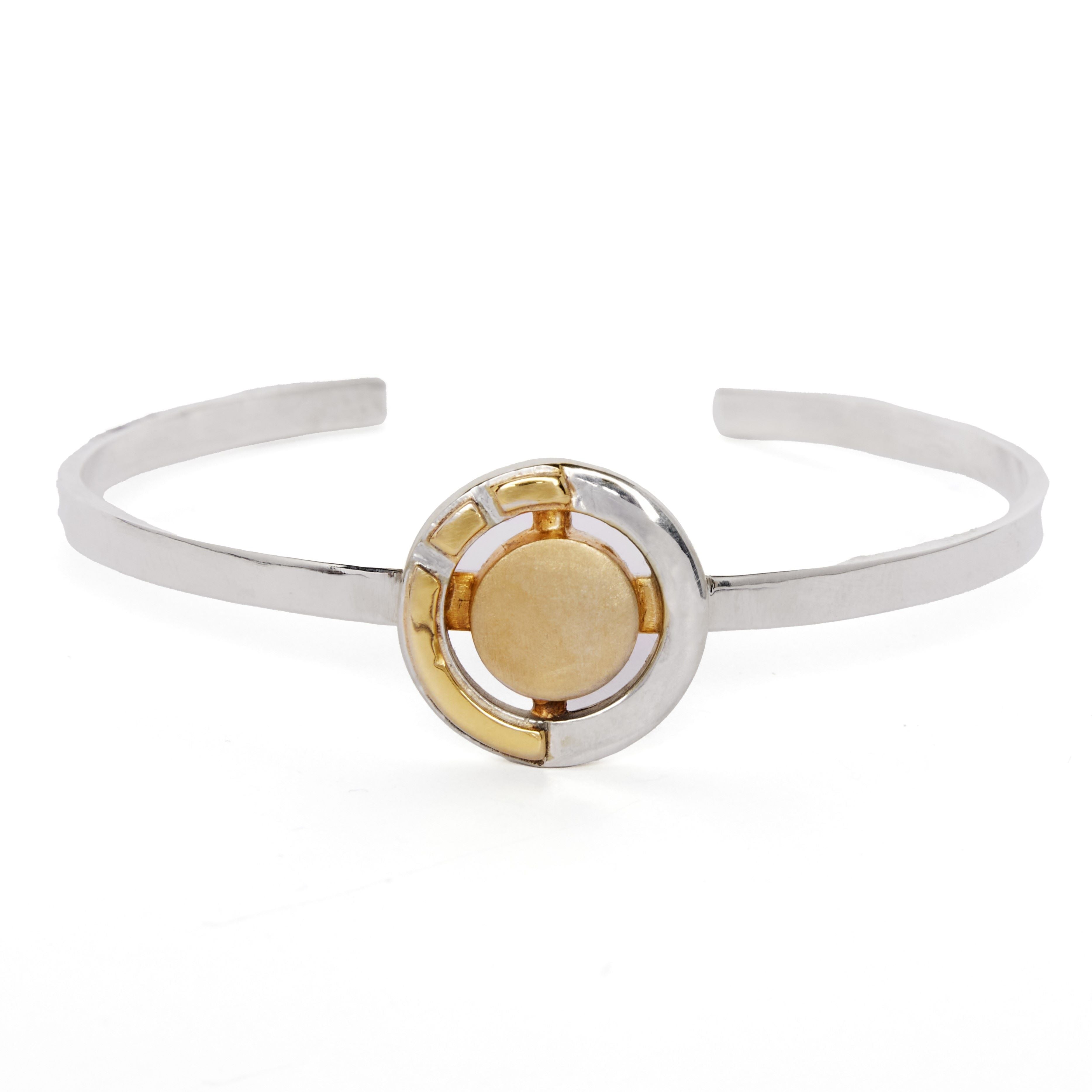 The Urú Cuff Silver & Gold by Gallardo & Blaine Designs is a sterling silver open Celtic cuff with a gold and silver geometric centerpiece and raised gold disc, inspired by Irish heritage jewelry traditions.