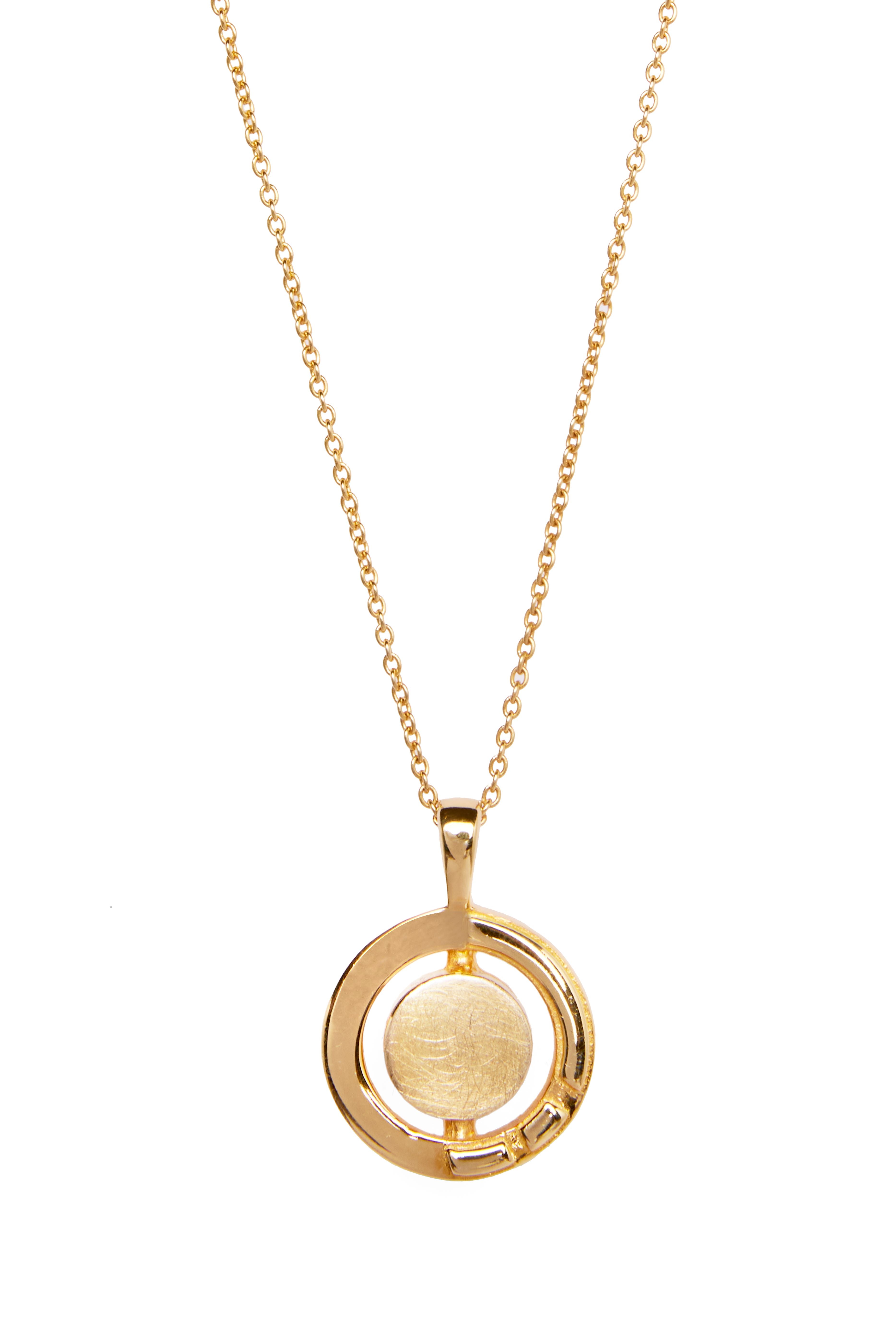 A gold Urú Small Pendant & Chain by Gallardo & Blaine Designs features a delicate chain and a circular pendant. The pendant consists of a large, brushed gold disc encircled by an open, polished gold ring. Drawing inspiration from Celtic tradition, the de