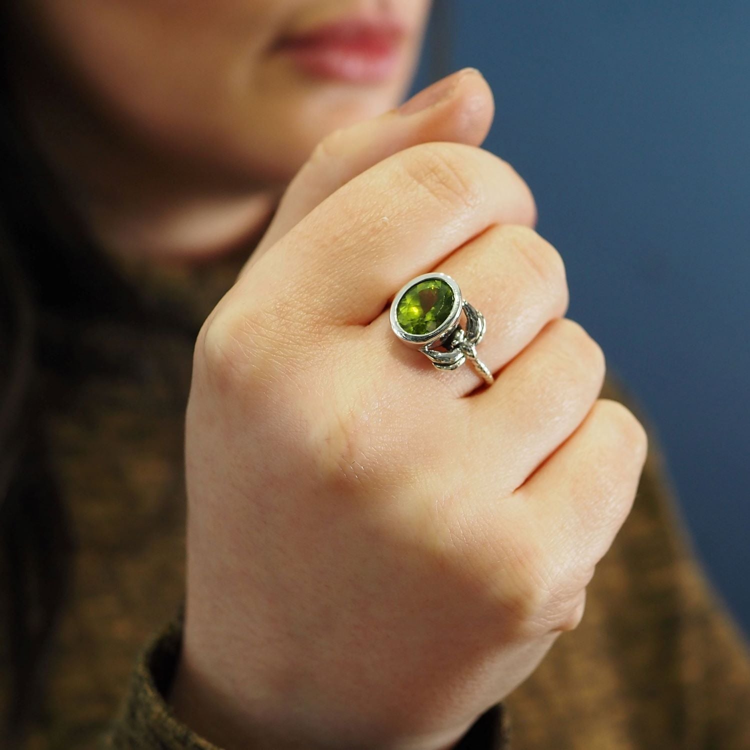 A close-up of a person's hand showing a delicate and dainty silver Daydream Ring in various gemstones by Gallardo & Blaine Designs. The person's face and background appear out of focus, adding to the allure of this timeless piece. The person is wearing a 