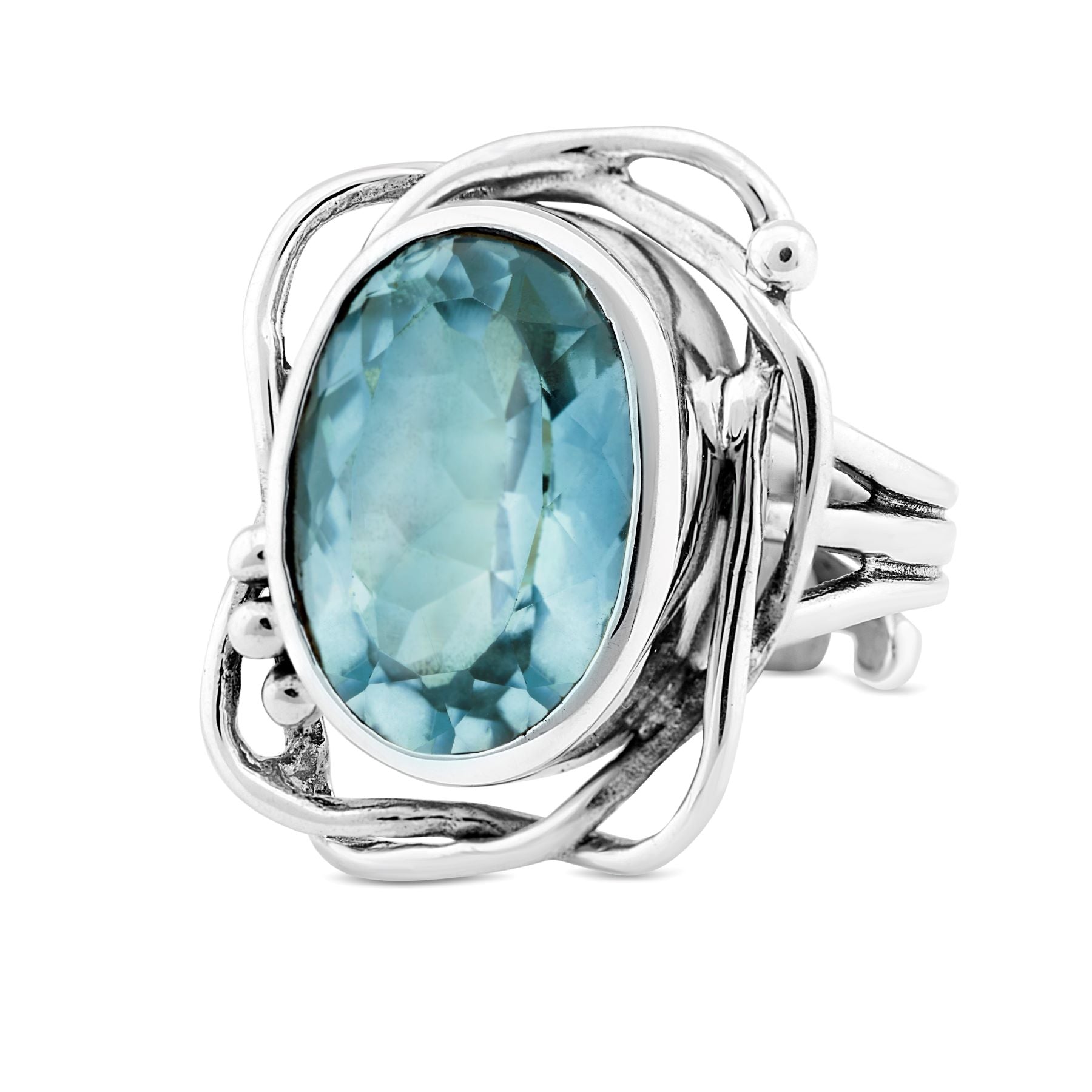 A silver ring with an abstract, wavy design features a large, oval-shaped blue gemstone at its center. The intricate silver setting wraps around the gemstone, giving this Gallardo & Blaine Designs Whirlpool Ring in various gemstones a modern and artistic 