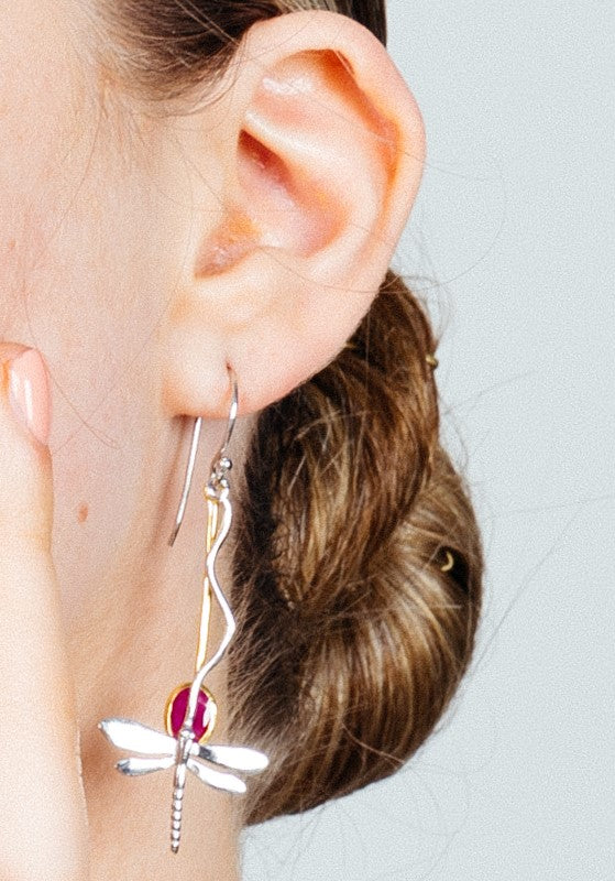 Close-up of a woman's ear adorned with a Willow Earring in Various Gemstones by Gallardo & Blaine Designs. Her hair is tied back in a bun, and she lightly touches her cheek with her fingers. The background is neutral, allowing the intricate detailing of t
